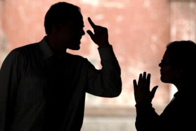 Pareja sentada en un sofá mirándose con calma después de resolver una discusión.