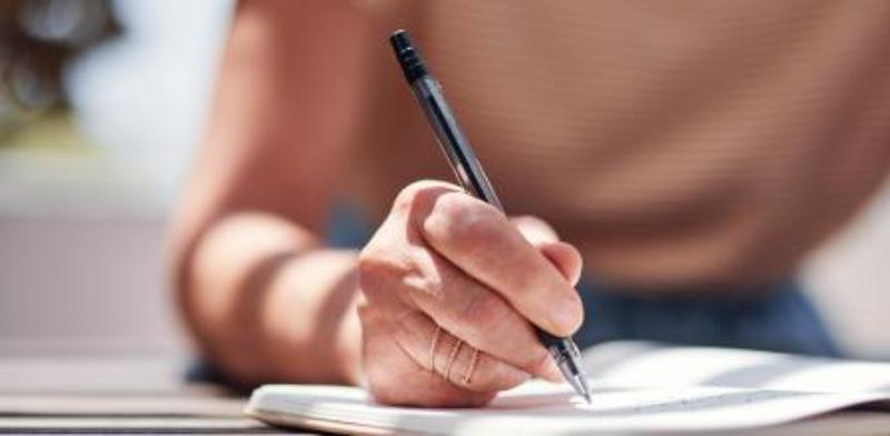 Persona escribiendo propósitos de Año Nuevo en una libreta, representando los retos para cumplir metas personales.