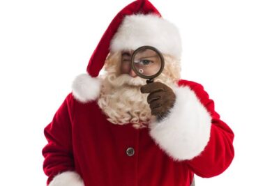 Papa Noel con lupa en el ojo, simbolizando consejos para cuidar la salud visual en Navidad.