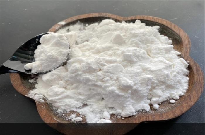 Un poco de suplemento de glicinato de magnesio en un cuenco de madera junto a una cuchara, simbolizando su consumo y lo efecivo que puede ser.