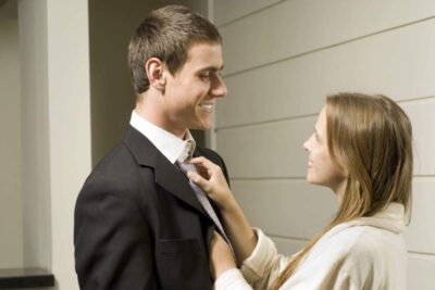 Pareja sentada en un sofá con expresiones serias, simbolizando conflictos por dinámicas parentales en la relación.